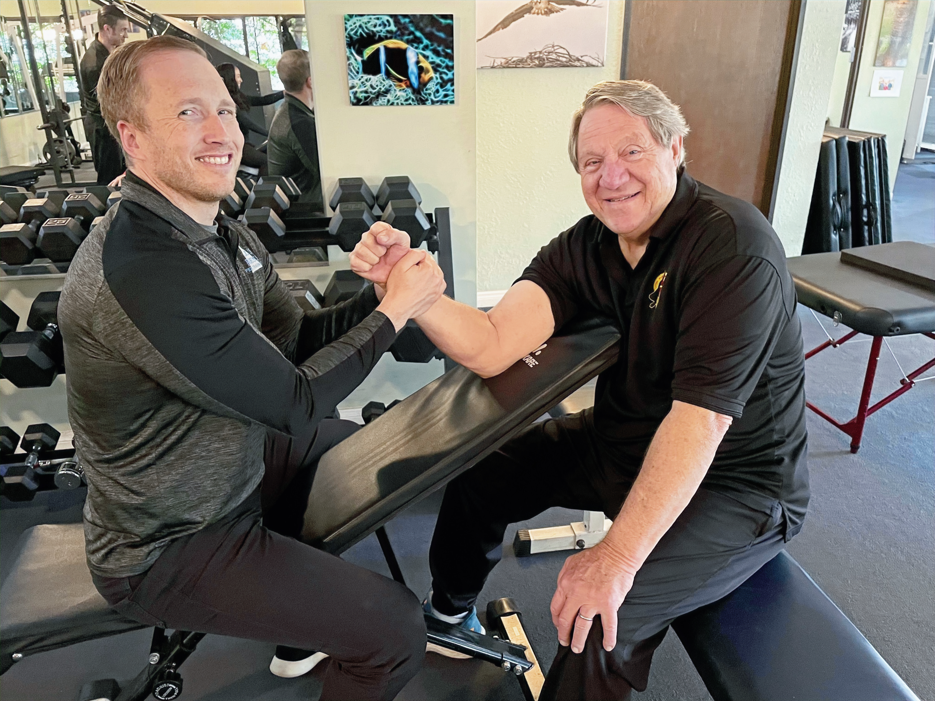 A trainer guiding a senior client through hands-on resistance training
